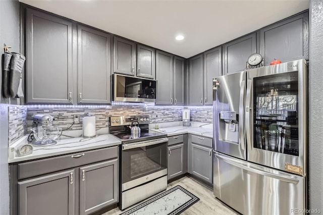 kitchen featuring recessed lighting, gray cabinetry, stainless steel appliances, light wood-style floors, and tasteful backsplash