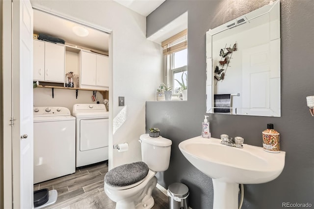 half bath with wood finish floors, toilet, washing machine and dryer, and a textured wall