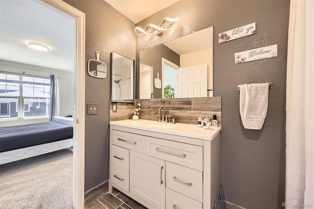 ensuite bathroom with vanity, a textured wall, and connected bathroom