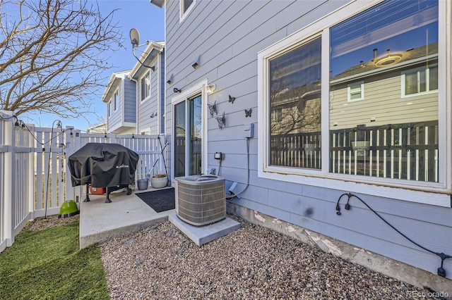 exterior space with central air condition unit, grilling area, and fence