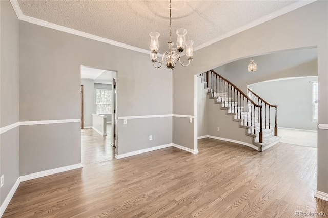 2141 Weatherstone Cir, Highlands Ranch, CO 80126 - unfurnished dining area with a chandelier, arched walkways, wood finished floors, a textured ceiling, and stairway