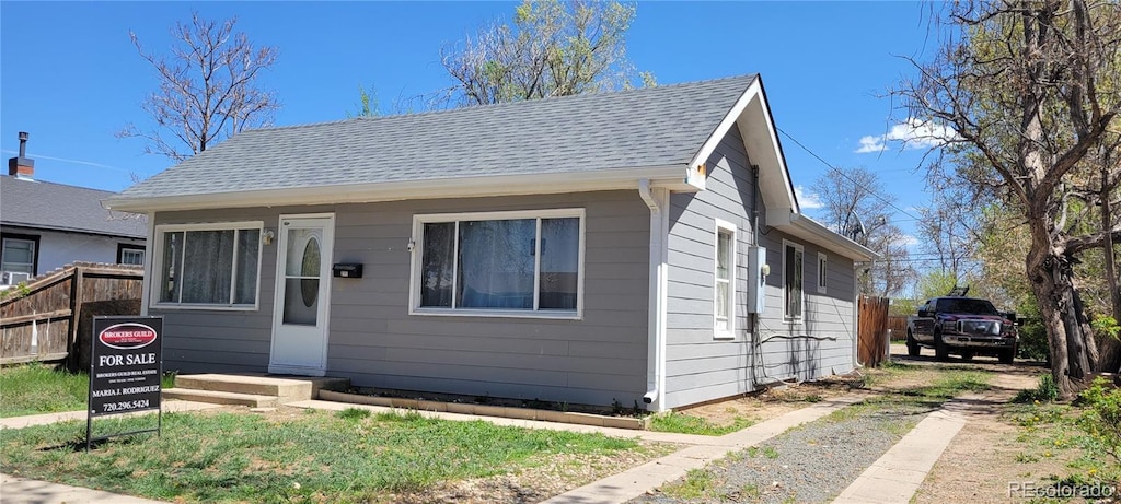 bungalow featuring fence, a shingled roof, and driveway