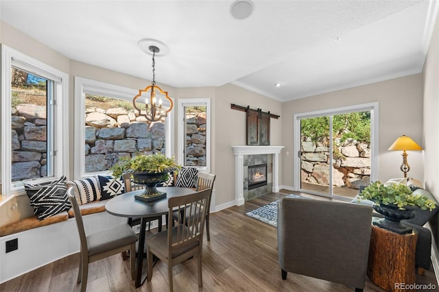 dining room featuring hardwood / wood-style flooring, plenty of natural light, a tile fireplace, and an inviting chandelier