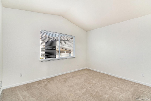 carpeted spare room featuring vaulted ceiling