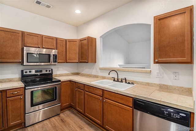 kitchen with appliances with stainless steel finishes, light hardwood / wood-style floors, and sink