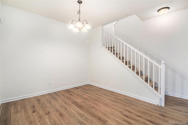 spare room featuring wood-type flooring and a notable chandelier