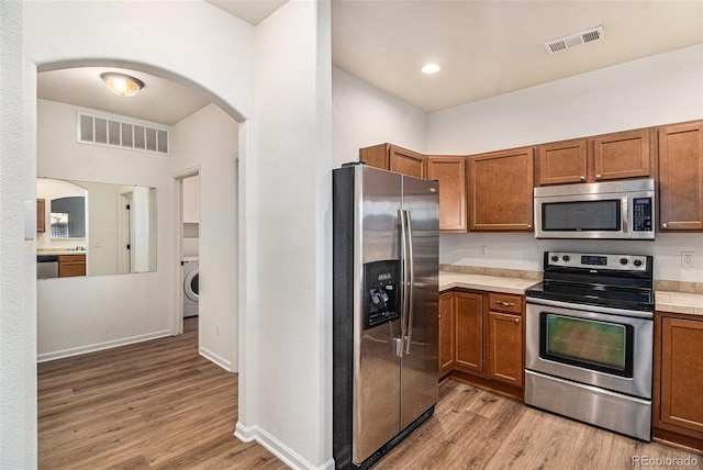 kitchen featuring light wood-type flooring, stainless steel appliances, and washer / clothes dryer