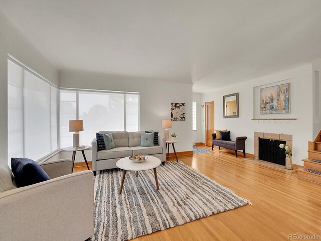 living room featuring a tiled fireplace and light wood-type flooring