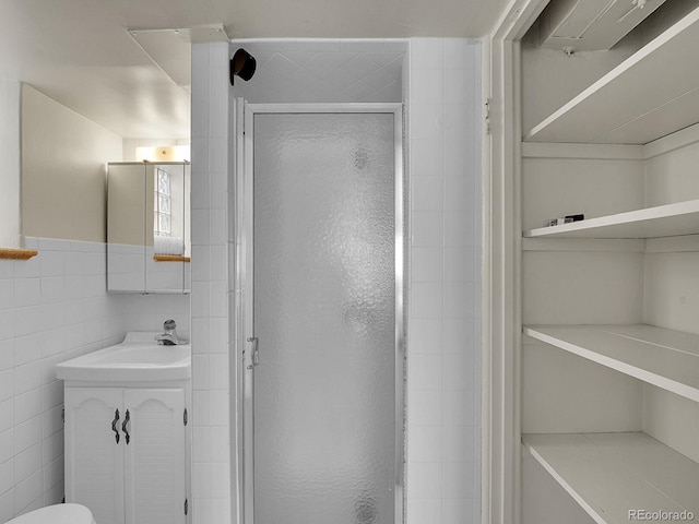 full bathroom with a closet, a shower stall, vanity, and tile walls