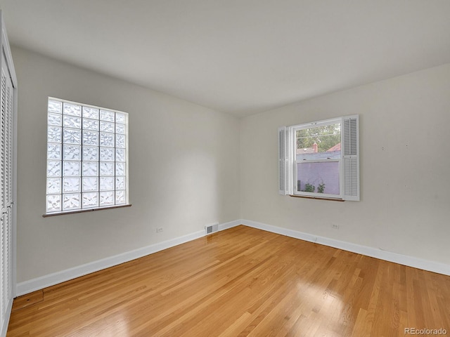 empty room featuring light wood finished floors, visible vents, and baseboards