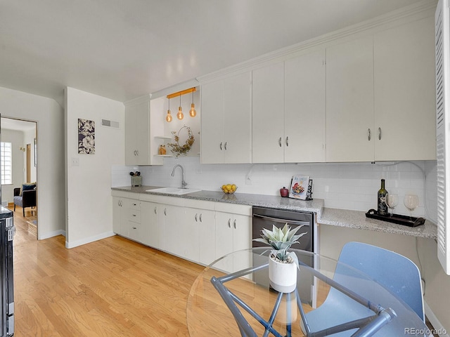 kitchen featuring black dishwasher, decorative light fixtures, visible vents, white cabinets, and a sink