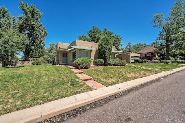 view of front of property featuring a front lawn, fence, and brick siding