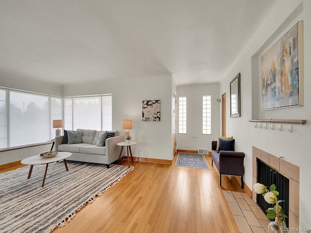 living room with light wood-style floors, baseboards, a fireplace, and visible vents