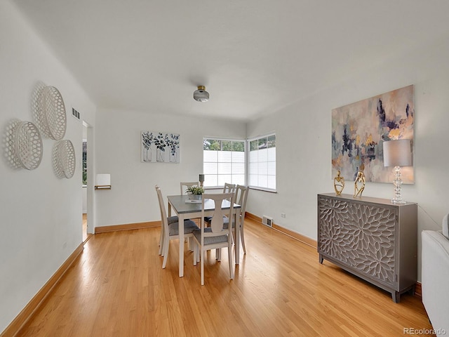 dining room featuring baseboards, visible vents, and light wood finished floors