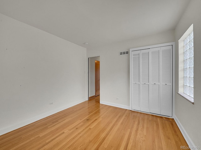 unfurnished bedroom with a closet, visible vents, light wood-style flooring, and baseboards