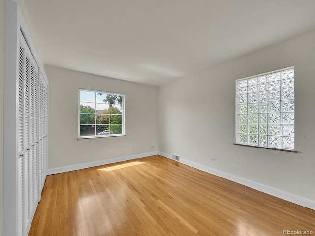 unfurnished bedroom with baseboards, a closet, visible vents, and light wood-style floors