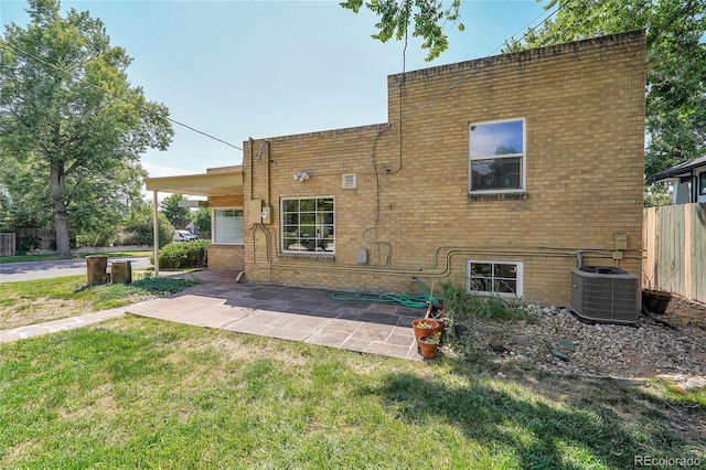 rear view of property with brick siding, a yard, central air condition unit, a patio area, and fence