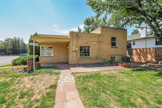 back of house featuring central AC unit, fence, a yard, a patio area, and brick siding