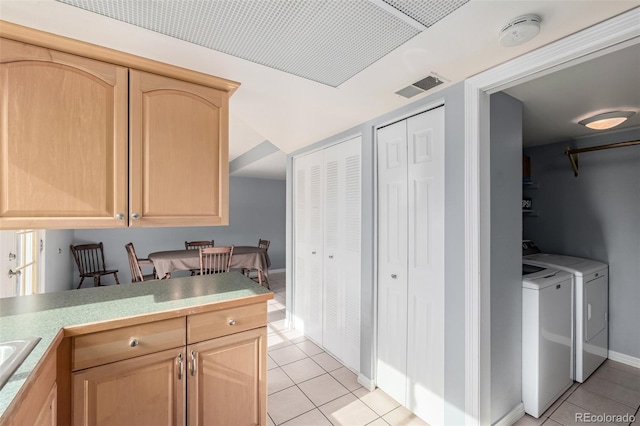 kitchen featuring washing machine and clothes dryer, light brown cabinetry, sink, and light tile patterned floors