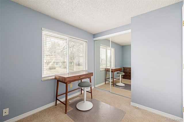 carpeted office featuring a textured ceiling