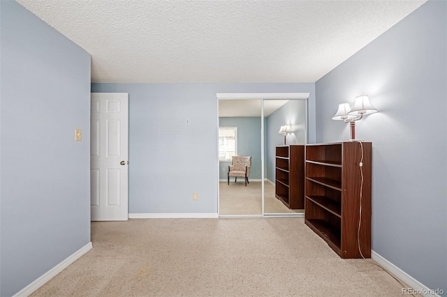 empty room with light carpet and a textured ceiling