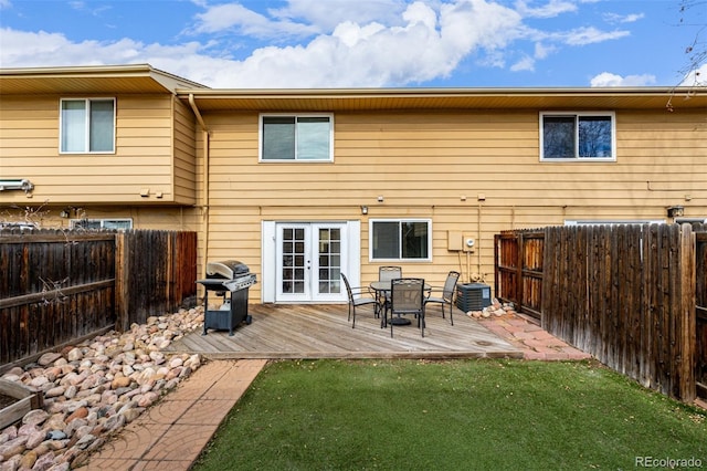 back of property with a wooden deck, a lawn, central AC unit, and french doors