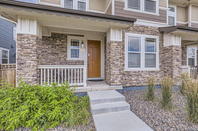 property entrance featuring board and batten siding, covered porch, and stone siding