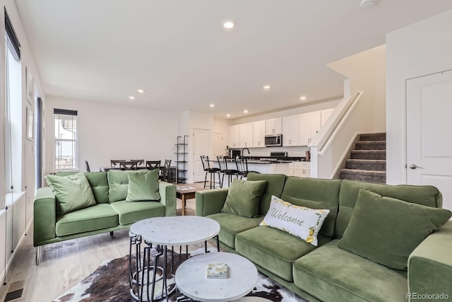 living area with recessed lighting, stairway, and light wood-style floors