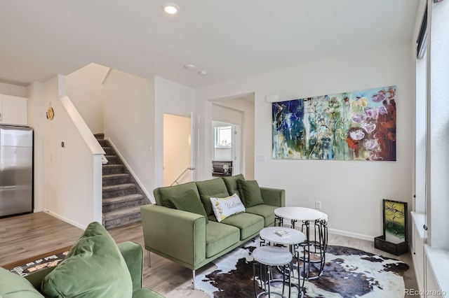 living room featuring stairs, baseboards, and light wood-type flooring