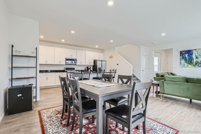 dining area with light wood-style floors, recessed lighting, baseboards, and stairs