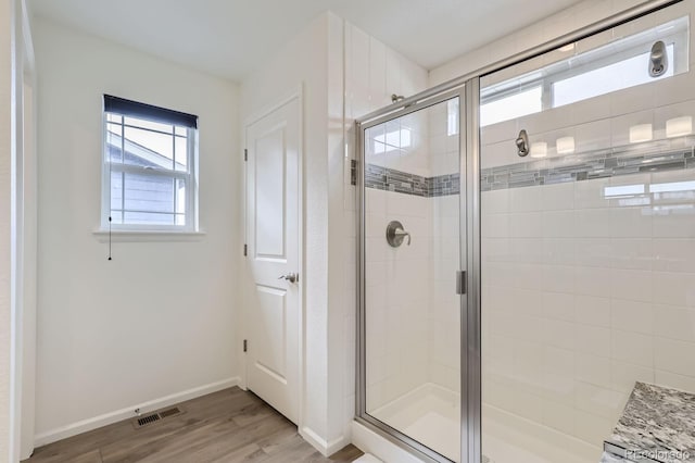 bathroom with wood finished floors, baseboards, a stall shower, and visible vents