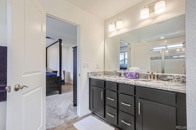 ensuite bathroom with a sink, a shower stall, ensuite bath, and double vanity
