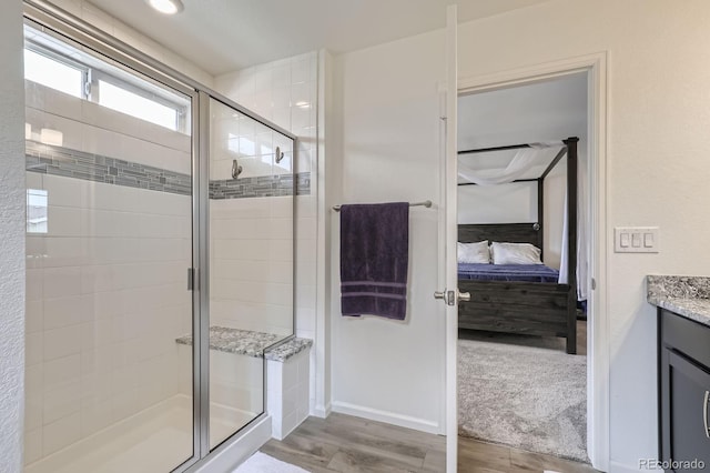 full bathroom featuring connected bathroom, a shower stall, wood finished floors, and vanity