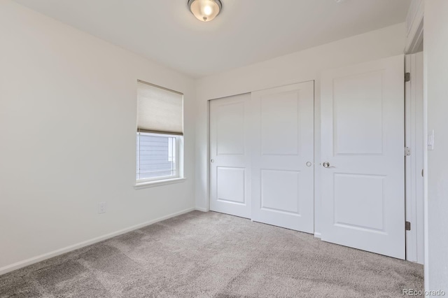 unfurnished bedroom with carpet floors, baseboards, and a closet