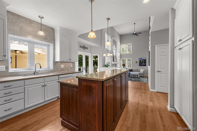 1564 S Uinta Way, Denver, CO 80231 - kitchen featuring a sink, ceiling fan, white cabinetry, open floor plan, and a towering ceiling