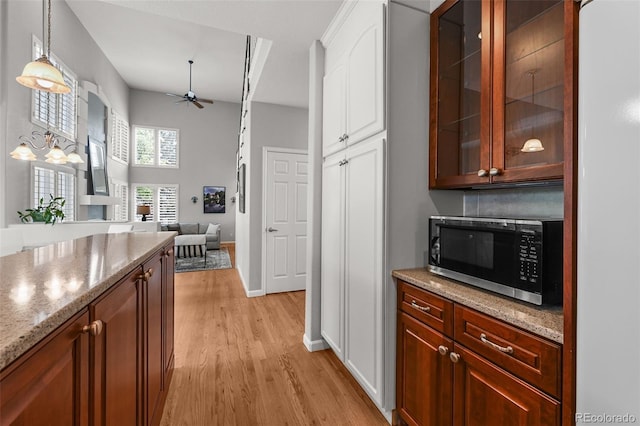 1564 S Uinta Way, Denver, CO 80231 - kitchen featuring stainless steel microwave, a ceiling fan, light wood-style flooring, glass insert cabinets, and white cabinets