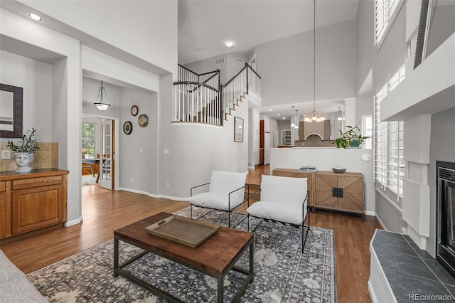 1564 S Uinta Way, Denver, CO 80231 - living room with wood finished floors, a tile fireplace, a towering ceiling, a chandelier, and stairs