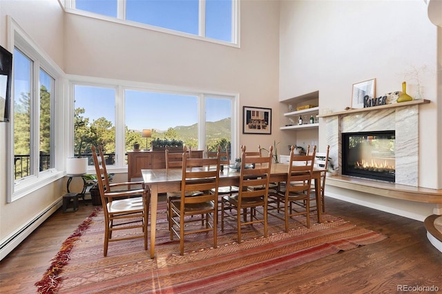 2873 Cortina Ln, Evergreen, CO 80439 - dining space featuring a baseboard radiator, a high ceiling, wood finished floors, and healthy amount of natural light