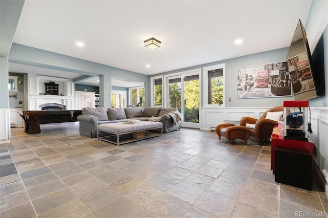 2873 Cortina Ln, Evergreen, CO 80439 - living room featuring stone tile flooring, a decorative wall, a fireplace, recessed lighting, and wainscoting