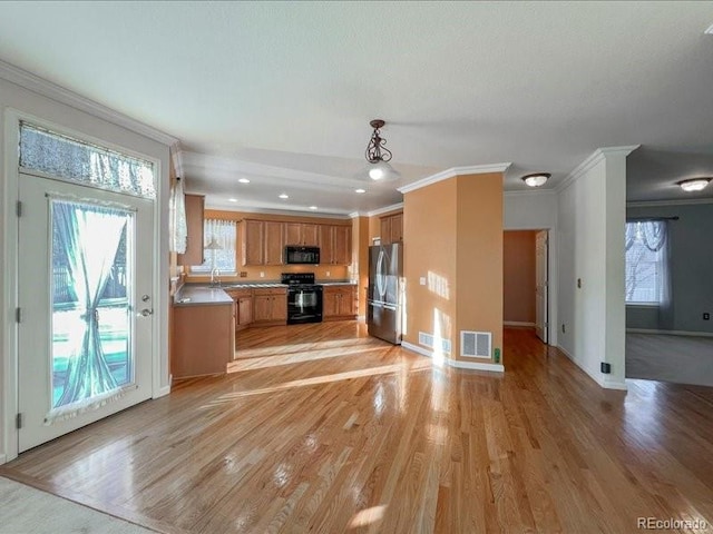 kitchen with decorative light fixtures, crown molding, black appliances, and light hardwood / wood-style floors