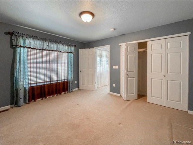 unfurnished bedroom with light carpet, a closet, and a textured ceiling