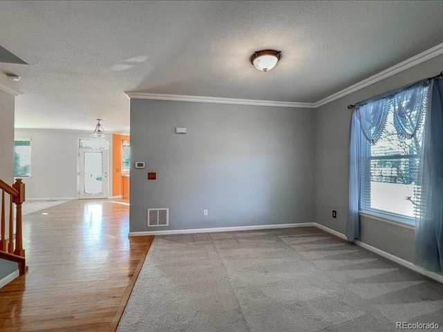 empty room with ornamental molding, light carpet, and a textured ceiling