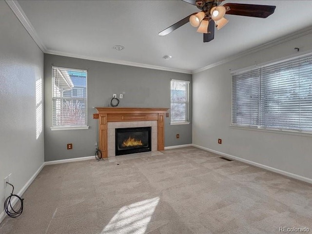 unfurnished living room featuring a tiled fireplace, light colored carpet, ornamental molding, and a healthy amount of sunlight