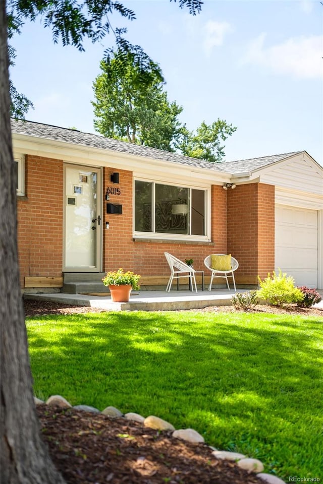 6015 Everett St, Arvada, CO 80004 - view of front facade with a front lawn, brick siding, and an attached garage