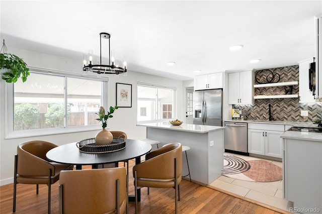 6015 Everett St, Arvada, CO 80004 - kitchen featuring appliances with stainless steel finishes, open shelves, backsplash, a chandelier, and light countertops