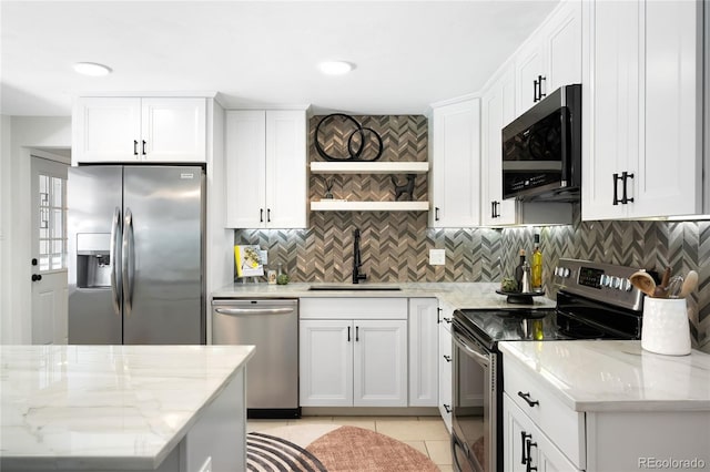 6015 Everett St, Arvada, CO 80004 - kitchen featuring appliances with stainless steel finishes, tasteful backsplash, light tile patterned flooring, white cabinetry, and light stone countertops