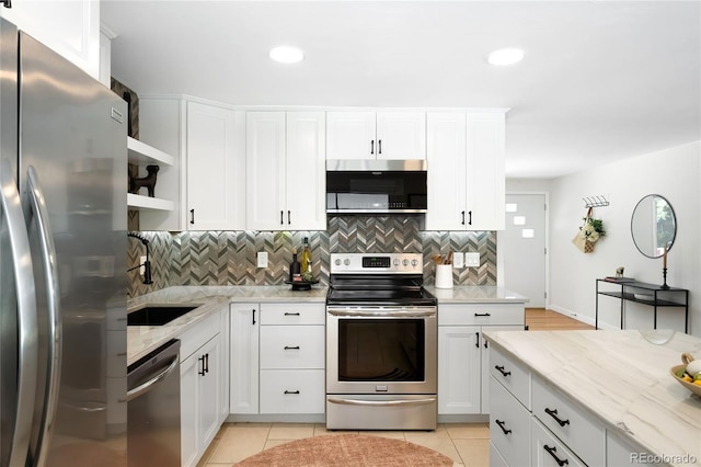 6015 Everett St, Arvada, CO 80004 - kitchen featuring appliances with stainless steel finishes, open shelves, tasteful backsplash, light stone counters, and white cabinetry