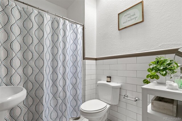 3725 Federal Blvd, Denver, CO 80211 - bathroom with a textured wall, a shower with shower curtain, a wainscoted wall, and tile walls