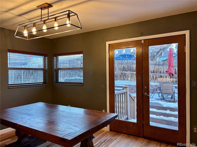 unfurnished dining area featuring an inviting chandelier, wood-type flooring, and french doors