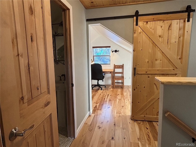 hallway featuring a barn door, wood ceiling, and light hardwood / wood-style flooring